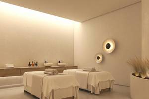 Spa-Behandlungsraum im Jaz Elite Amara Hotel mit zwei Behandlungstischen, weißen Wänden und Deckenbeleuchtung.
