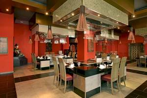 Innenbereich des Restaurants im Iberostar Grand Bavaro Hotel mit roten Wänden, modernen Möbeln und einer Buddha-Statue.