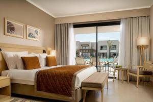 Hotelzimmer im Jaz Elite Amara mit Poolblick, einem großen Bett und bequemen Sitzmöbeln.
