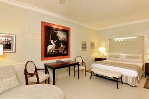 Suite-Schlafzimmer im JOIA Bávaro by Iberostar mit Doppelbett, Schreibtisch und Stühle.