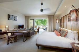 Schlafzimmer im Constance Ephelia Resort mit großem Bett, Schreibtisch und Balkon.