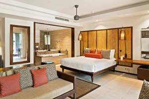 Innenansicht der Luxus-Suite im Constance Ephelia Resort mit Bett, Sofa und Badezimmer.