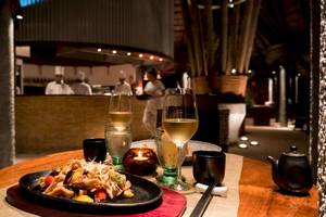 Foto von einem Tisch im Constance Ephelia Resort mit Speisen, Getränken und Kellnern im Hintergrund.