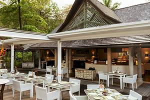 Außenbereich des Constance Ephelia Resorts mit Tisch und Stühlen, umgeben von Pflanzen.