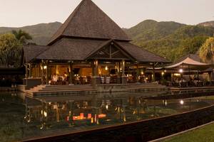 Außenansicht des Constance Ephelia Resorts mit Swimmingpool und Bergpanorama im Hintergrund.