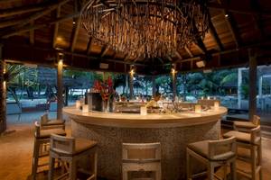 Cocktailbar im Constance Ephelia Resort mit Blick auf den Strand und Palmen.