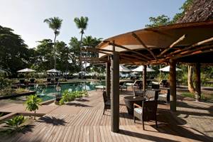 Terrasse im Constance Ephelia Resort mit Tischen, Stühlen und Sonnenschirmen am Swimmingpool.
