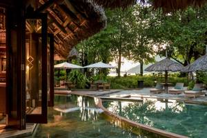 Außenbereich des Constance Ephelia Resorts mit Pool, Sonnenschirmen und Loungemöbeln.