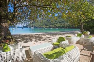 Lounge-Set am Strand des Constance Ephelia Resorts mit Blick auf das Meer und Berge.