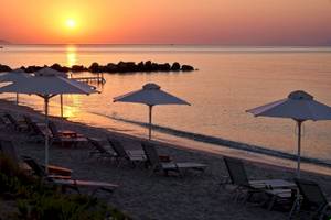 Sonnenuntergang am Strand des Atlantica Beach Resort Kos mit vielen Sonnenschirmen und Liegestühlen