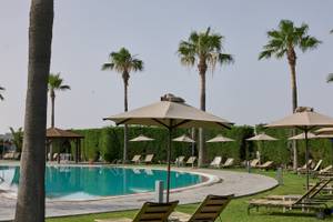 Poolbereich des Atlantica Beach Resort Kos mit Sonnenliegen und Sonnenschirmen.