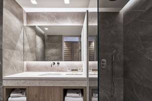 Modernes Badezimmer im Atlantica Beach Resort Kos mit grauen Marmorwänden und einer großen Spiegelfläche.