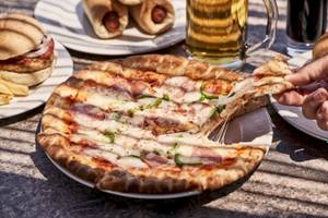 Tisch mit einer geschnittenen Pizza, Bier, alkoholfreien Getränken und Sandwiches.