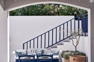 Sitzecke im Garten des Atlantica Beach Resort Kos mit blauen Stühlen und Tisch.