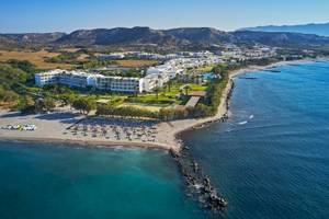 Gesamtansicht des Atlantica Beach Resort Kos am Strand mit vielen Liegestühlen und Hotelgebäuden.
