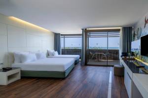 Innenansicht eines Hotelzimmers im Nirvana Cosmopolitan mit zwei Betten und Meerblick.