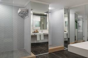 Badezimmer im Nirvana Cosmopolitan Hotel mit Marmorboden, Glasdusche und Badewanne.