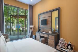 Ein Hotelzimmer im Nirvana Cosmopolitan mit Panoramafenstern, die auf einen Garten und eine Terrasse mit Tischen und Stühlen hinausführen.