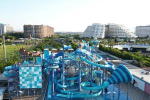 Luftaufnahme des Nirvana Cosmopolitan Wasserparks mit vielen Rutschen und Gebäuden im Hintergrund.