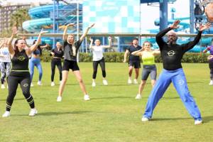 Fitnessgruppe im Nirvana Cosmopolitan Hotelgarten vor einer Wasserrutsche