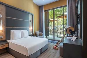 Innenansicht eines Hotelzimmers des Nirvana Cosmopolitan Hotels mit Bett, Nachttischen und offenem Balkon.