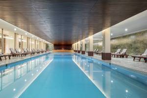 Innenpool des Nirvana Cosmopolitan Hotels mit Liegen und beleuchteten Wänden.