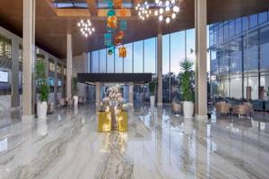 Empfangsbereich des Nirvana Cosmopolitan Hotels mit Marmorboden, großen Fenstern und modernen Möbeln.