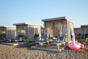 Lounges am Strand des Nirvana Cosmopolitan Hotels mit Flamingo-Pool und Sonnenliegen