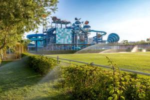 Wasserpark des Nirvana Cosmopolitan Hotels mit großen Wasserrutschen und grüner Rasenfläche.