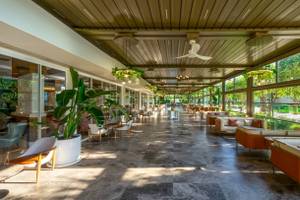 Innenbereich des Nirvana Cosmopolitan Hotels mit Sofas, Tischen, Pflanzen und Deckenventilatoren.