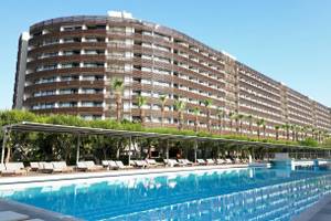 Das Nirvana Cosmopolitan Hotel mit einem großen Swimmingpool und Sonnenliegen davor.