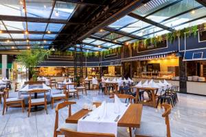 Innenansicht des Restaurants im Nirvana Cosmopolitan Hotel mit Tischen, Stühlen und einer Theke.