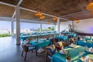 Innenbereich des Nirvana Cosmopolitan Hotels, Restaurant mit blauen Tischen und Stühlen, dekoriert mit Pflanzen und Lampen.