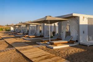 Reihe von Strandlounges mit Sonnenschirmen und Sonnenliegen auf einem Holzsteg