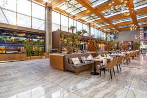 Innenbereich des Nirvana Cosmopolitan Hotels mit gepolsterten Bänken und runden Tischen.