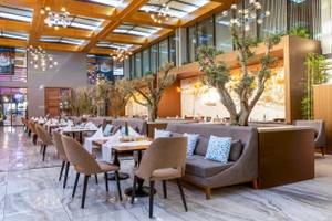 Interieur des Restaurants im Nirvana Cosmopolitan Hotel mit Sitzgelegenheiten und Esstischen.
