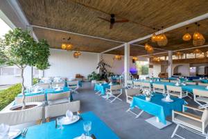 Innenbereich des Nirvana Cosmopolitan Hotels mit blauen Tischen und Stühlen, dekorierten Lampen und einer Statue.