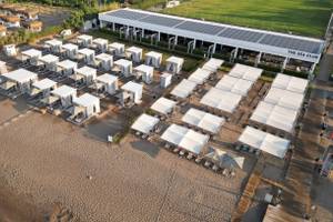 Luftaufnahme des Nirvana Cosmopolitan Hotels mit weißen Zelten und Solarmodulen am Strand