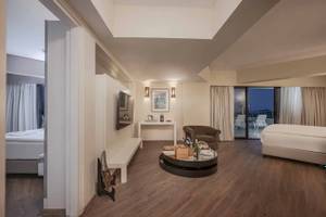 Innenansicht einer Hotelsuite im Megasaray Resort Side mit Wohnzimmer, Schlafzimmer und Balkon.