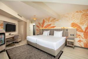 Doppelzimmer im Megasaray Resort Side mit zwei Betten, Fernseher, Schreibtisch und tropischen Wandmustern.