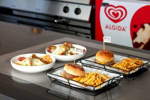 Drei Gerichte von Megasaray Resort Side: Burger, Pommes und Salat, serviert auf einer Theke.