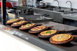 Mehrere Pizzen auf Holzplatten in der Küche des Megasaray Resort Side.