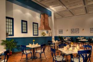 Innenbereich des Jaz Grand Marsa Restaurants mit blauen Stühlen und Tischen.