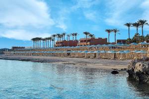 Strand des Jaz Grand Marsa Hotels mit Palmen und Sonnenschirmen