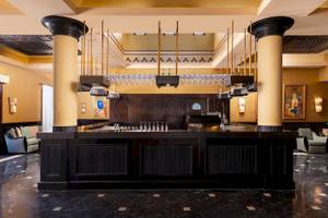 Innenbereich der Bar im Jaz Lamaya Resort Hotel mit schwarzen Theken und hohen Säulen.