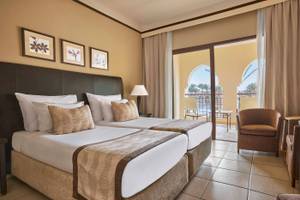 Doppelzimmer im Jaz Lamaya Resort mit zwei Betten und Balkon mit Blick auf den Pool.