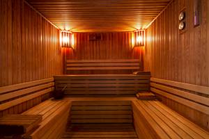 Eine leere Holzsauna mit warmem Licht und Hockern im Jaz Lamaya Resort