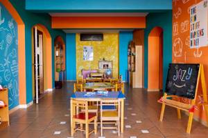 Foto von einem farbenfrohen Kinderzimmer im Jaz Lamaya Resort mit bunten Wänden, Tischen und Stühlen.