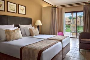 Doppelzimmer im Jaz Lamaya Resort mit zwei Betten, Lampe, Sessel und Balkon.