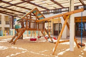 Spielplatz im Jaz Lamaya Resort mit Sandboden, Holzspielgeräten und Überdachung.